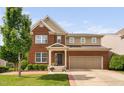 Charming brick two-story home featuring a front-facing two-car garage, well-manicured lawn, and mature tree at 5028 Blue Jack Oak Dr, Cary, NC 27519