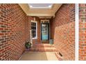 Inviting brick-covered front porch with a welcoming welcome sign, beautiful flower arrangement, and a stylish blue front door at 6708 Wavcott Dr, Fuquay Varina, NC 27526