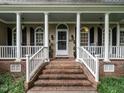 Inviting covered front porch with brick steps and classic white columns at 820 Parkridge Dr, Clayton, NC 27527