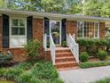 Close-up of a charming brick home's front entrance with white railing and black shutters at 926 Wimbleton Dr, Raleigh, NC 27609