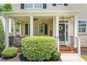 Inviting front porch with brick accents, white columns, hanging plants, and a welcoming wreath on the door at 100 Fountain Springs Rd, Holly Springs, NC 27540