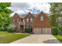 Charming two-story brick home with a well-manicured lawn, two-car garage, and classic architectural details at 111 Revere Forest Ct, Cary, NC 27519
