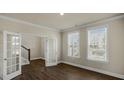A bright living room with hardwood floors, two windows, and glass french doors at 1113 Dartford Green Pl, Wake Forest, NC 27587