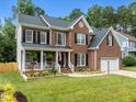 Attractive brick home with a covered porch, manicured lawn, and an attached garage at 114 Council Gap Ct, Cary, NC 27513