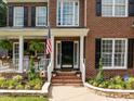 Charming front entrance with brick steps, black door, and lush landscaping at 114 Council Gap Ct, Cary, NC 27513