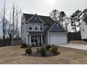 Well-manicured front yard with a two-story home featuring gray siding, a garage, and tasteful landscaping at 185 Bourne Dr, Franklinton, NC 27525