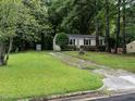 Quaint single-story home surrounded by trees, featuring a spacious front lawn with driveway at 203 Lane Of Sir Kay, Garner, NC 27529