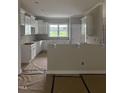An incomplete kitchen with white cabinets, light gray walls and unfinished flooring covered with construction materials at 2776 Rains Mill Rd, Princeton, NC 27569