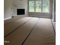 Bright living room featuring a fireplace, mantel and large windows with unfinished flooring covered with construction materials at 2776 Rains Mill Rd, Princeton, NC 27569