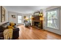Cozy living room with a brick fireplace, hardwood floors, and large windows offering natural light at 308 Trappers Sack Rd, Cary, NC 27513