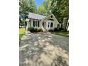 Inviting single-story house showcases a spacious driveway, mature trees, and classic design elements at 5 Sue Ann Ct, Durham, NC 27704