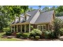 A delightful side view of a brick home showcases the inviting front porch and beautifully landscaped surroundings at 901 Tamaras Cir, Wake Forest, NC 27587