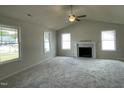 Spacious living room with a cozy fireplace, vaulted ceiling, and multiple windows for natural light at 116 Oakfield Trace Dr, Four Oaks, NC 27524