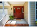 Covered front porch featuring a red front door, decorative sidelights, and brick-lined landing with a potted plant at 13 Boxwood Dr, Durham, NC 27713