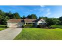 Inviting single-story home with a paved driveway, lush green lawn, and mature trees in the background at 131 Abacos Ct, Clayton, NC 27520