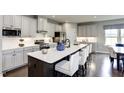 Open kitchen with white cabinets, stainless steel appliances, a large island with seating, and dining area at 199 Glen Hollow Dr, Raleigh, NC 27604