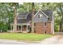 View of home's full yard and two-story elevation featuring brick facade, gray siding, and inviting covered front porch at 205 Northfield Dr, Raleigh, NC 27609