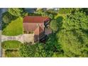 Aerial view of home featuring a red roof, backyard patio, and lush surrounding trees at 2257 Delaney Dr, Burlington, NC 27215