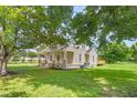 View of a charming home with a well-manicured lawn and deck area from under the shade of a tree at 232 S Marshall St, Graham, NC 27253