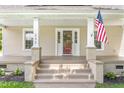 Inviting front porch with sturdy white columns, an American flag, and a freshly painted red front door at 232 S Marshall St, Graham, NC 27253