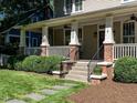The cozy front porch features brick detailing, white columns, and well-maintained landscaping at 300 W Roanoke Park Dr, Raleigh, NC 27608