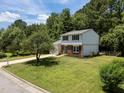 Charming two-story home with a brick facade, a blue door, a well manicured lawn, and mature trees at 505 Drolmond Dr, Raleigh, NC 27615