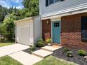 Close-up of the entrance featuring a brick facade, blue door, manicured landscaping, and attached one car garage at 505 Drolmond Dr, Raleigh, NC 27615