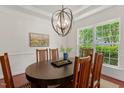Bright dining room with a modern chandelier, hardwood floors, and a window with outside view at 507 Turmeric Ln, Durham, NC 27713