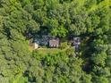 Aerial view showcases the home surrounded by lush, mature trees, offering a private and serene setting at 5216 Woods End Rd, Hillsborough, NC 27278