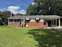 Classic brick home featuring a cozy front porch and an attached covered carport for convenient parking at 607 S Smithfield Rd, Knightdale, NC 27545