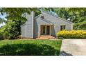 The front of a home has a gray, modern design, featuring a chimney and lush green grass at 7309 Forest Glade Ct, Raleigh, NC 27615