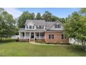 Inviting two-story home with a charming covered front porch, brick accents, and well-maintained landscaping at 81 Northcliff Ct, Clayton, NC 27527