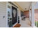 Inviting front porch featuring rocking chairs, decorative door, and beautiful brick accents at 81 Northcliff Ct, Clayton, NC 27527