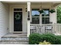 Inviting front porch with charming decor, featuring hanging plants, seating and stylish accessories at 857 Stable Fern Dr, Fuquay Varina, NC 27526