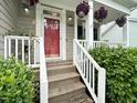 Inviting front porch with a red door, white railings, and lush green plants enhancing curb appeal at 8640 Swarthmore Dr, Raleigh, NC 27615