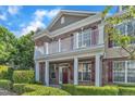 Charming brick townhouse with a covered front porch, a second-story balcony, and neatly trimmed landscaping at 10511 Sablewood Dr # 107, Raleigh, NC 27617