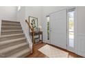Bright entryway with wood floors, stairway, white door, and side window at 110 Bonhill Ct, Apex, NC 27502