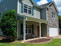 Charming two-story home featuring stone accents, green shutters, manicured lawn, and inviting front porch at 1122 Birkdale Dr, Mebane, NC 27302