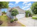 Home exterior showcasing a spacious two-car garage, lush landscaping, and a well-kept lawn at 1204 E Rosedale Creek Dr, Durham, NC 27703