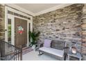 Inviting front porch with stone wall, bench, potted plant, and charming decor at 1413 Lily Creek Dr, Cary, NC 27518