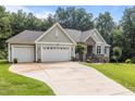 Attractive home showcasing a spacious three-car garage, stone accents, and well-kept landscaping at 186 Ross Dr, Pittsboro, NC 27312