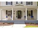 Inviting front porch featuring rocking chairs, stylish seating, a wreath-adorned door, and well-kept landscaping at 1990 Ferbow St, Creedmoor, NC 27522