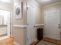 Clean hallway with hardwood floors, crisp white trim, and doors leading to the bathroom and exterior at 3652 E Cotton Gin Dr, Clayton, NC 27527
