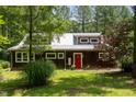 Daytime exterior showing a quaint home with a red door, set amongst lush greenery at 3822 Chicken Bridge Rd, Pittsboro, NC 27312