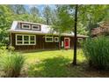 Exterior view of the home featuring a metal roof, green lawn and bright red front door at 3822 Chicken Bridge Rd, Pittsboro, NC 27312