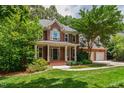 A charming brick home featuring a welcoming front porch with white columns, lush landscaping, and a well-maintained lawn at 5123 Richland Dr, Raleigh, NC 27612