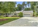 Inviting single-story home with an attached two-car garage and long driveway lined with green trees at 821 Van Thomas Dr, Raleigh, NC 27615