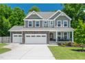 Charming two-story home showcasing a stone facade, covered porch, attached two-car garage and manicured lawn at 8341 Running Fern Way, Willow Springs, NC 27592