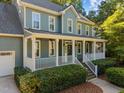 Home featuring a covered porch with white railings and green siding at 8412 Old Deer Trl, Raleigh, NC 27615