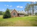 Beautiful brick home with a charming front porch and dormer windows surrounded by lush greenery at 100 Martindale Dr, Youngsville, NC 27596